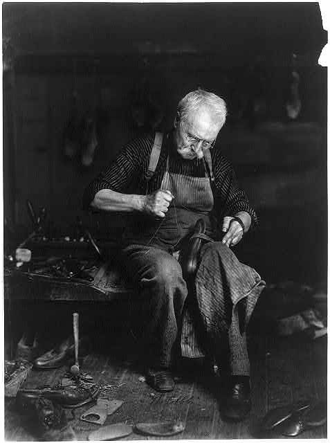 A cobbler resoling a shoe at his bench, 1901